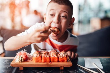 Çocuk açık kafede suşi yemeyi seviyor.