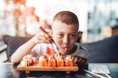 Çocuk açık kafede suşi yemeyi seviyor.