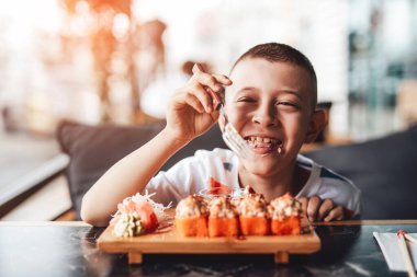 Çocuk açık kafede suşi yemeyi seviyor.