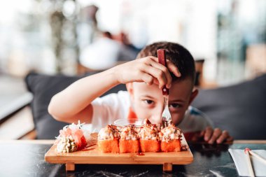 Çocuk açık kafede suşi yemeyi seviyor.