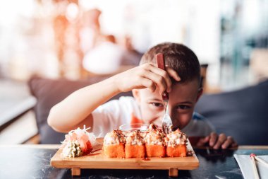 Çocuk açık kafede suşi yemeyi seviyor.