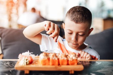 Çocuk açık kafede suşi yemeyi seviyor.
