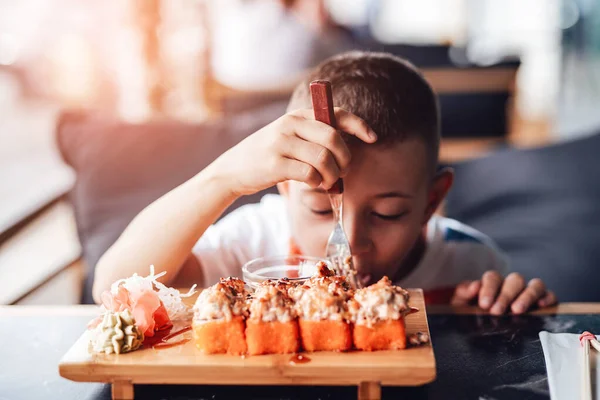 Çocuk açık kafede suşi yemeyi seviyor.