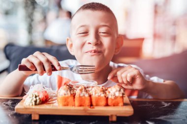 Çocuk açık kafede suşi yemeyi seviyor.
