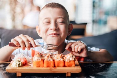 Çocuk açık kafede suşi yemeyi seviyor.