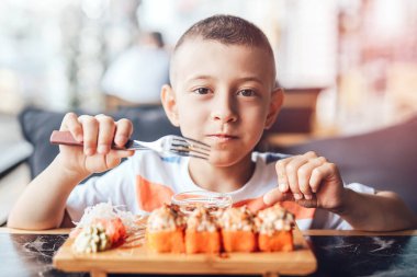Çocuk açık kafede suşi yemeyi seviyor.