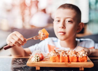 Çocuk açık kafede suşi yemeyi seviyor.