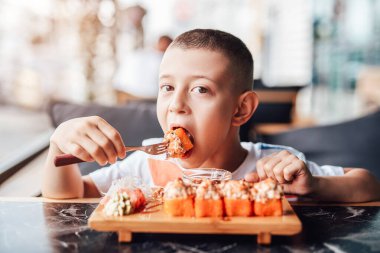 Çocuk açık kafede suşi yemeyi seviyor.