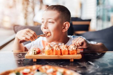 Çocuk açık kafede suşi yemeyi seviyor.