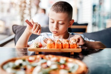 Çocuk açık kafede suşi yemeyi seviyor.