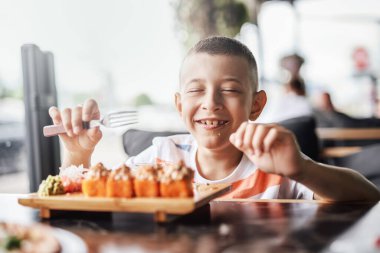 Çocuk açık kafede suşi yemeyi seviyor.
