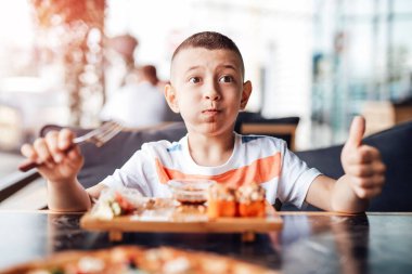 Çocuk açık kafede suşi yemeyi seviyor.