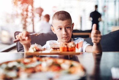 Çocuk açık kafede suşi yemeyi seviyor.