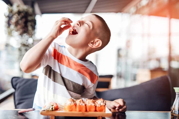 男孩喜欢在户外咖啡馆里吃寿司卷 — 图库照片