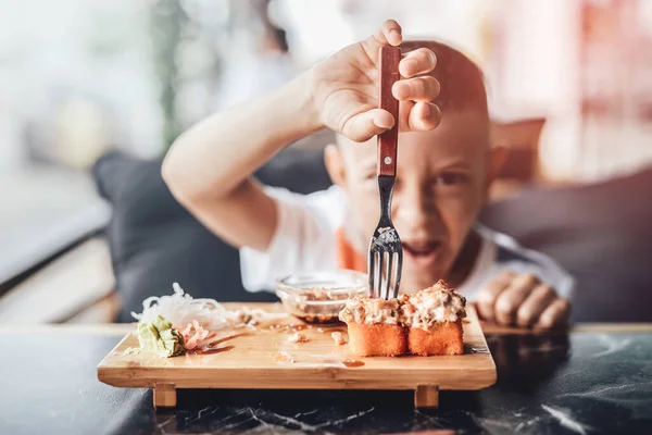 Chlapec má rád jíst sushi rolky ve venkovní kavárně — Stock fotografie