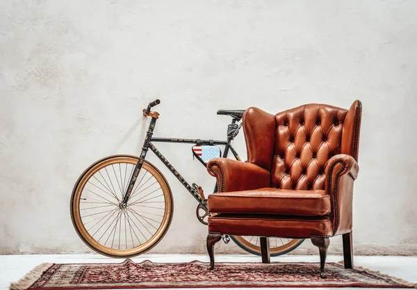 Изготовленный на заказ велосипед, старый ковер и роскошное ретро-кресло в комнате — стоковое фото