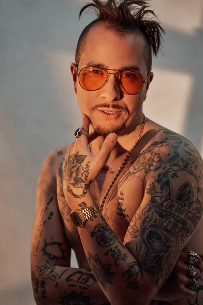 Retrato de un hombre sin camisa con corte de pelo expresivo y cuerpo tatuado en gafas de sol — Foto de Stock