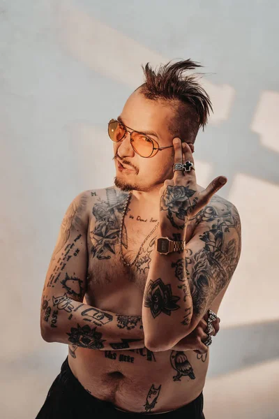 Porträt eines hemdlosen Mannes mit ausdrucksstarkem Haarschnitt und tätowiertem Körper mit Sonnenbrille — Stockfoto