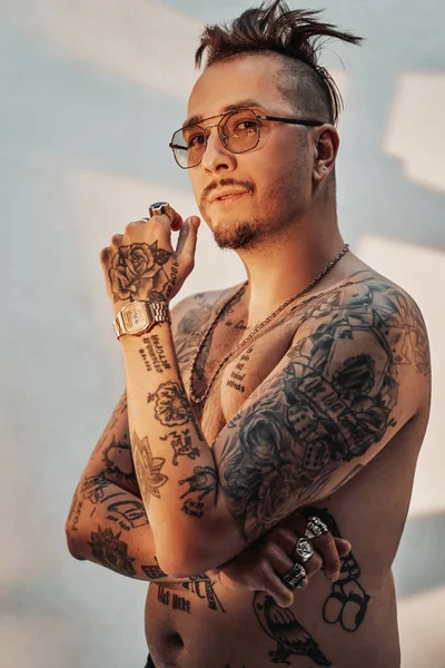 Retrato de un hombre sin camisa con corte de pelo expresivo y cuerpo tatuado en gafas de sol —  Fotos de Stock
