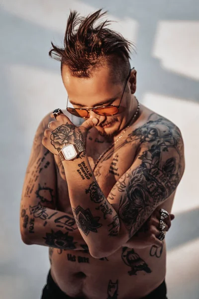 Retrato de un hombre sin camisa con corte de pelo expresivo y cuerpo tatuado en gafas de sol — Foto de Stock