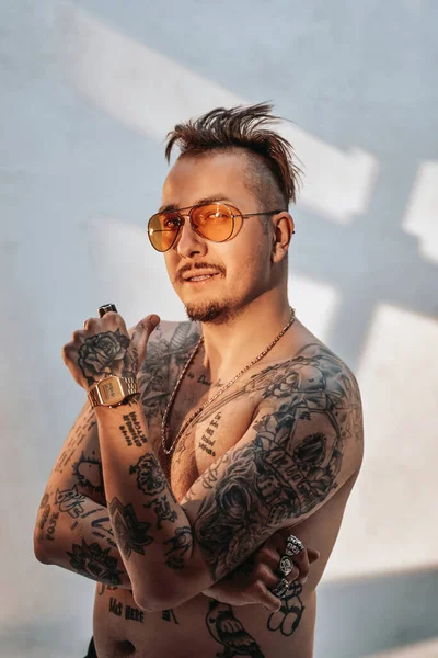 Retrato de un hombre sin camisa con corte de pelo expresivo y cuerpo tatuado en gafas de sol —  Fotos de Stock