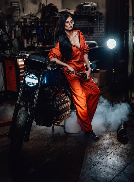 Linda morena apoiada em uma motocicleta preta — Fotografia de Stock