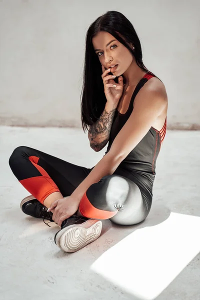 Roztomilá a krásná brunetka dívka s tetováním v černé teplákové soupravě — Stock fotografie