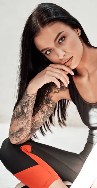 Roztomilá a krásná brunetka dívka s tetováním v černé teplákové soupravě — Stock fotografie