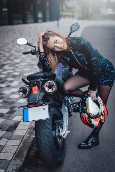 시내의 귀여운 소녀와 그가 타고 있는 어둡고 평상복 스러운 오토바이 — 스톡 사진