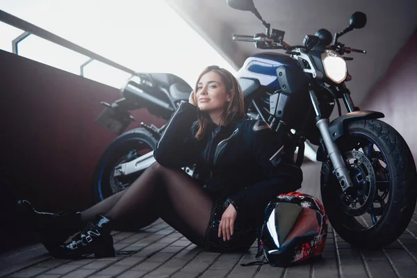 Bruin haar vrouwelijke motorrijder met haar krachtige moderne motorfiets — Stockfoto