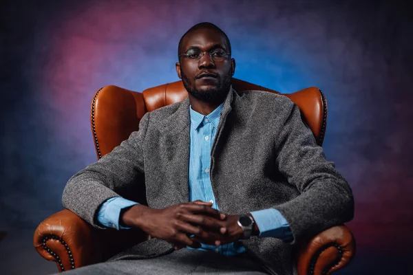 A serious african man looking and sitting on expensive seat — Stock Photo, Image