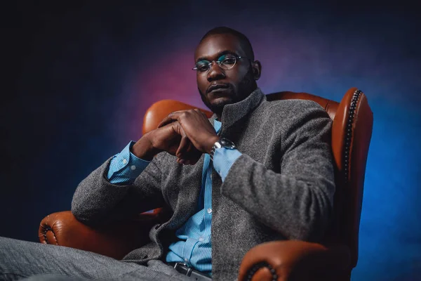 A casual leather chair and male blackskinned business person on it — Stock Photo, Image