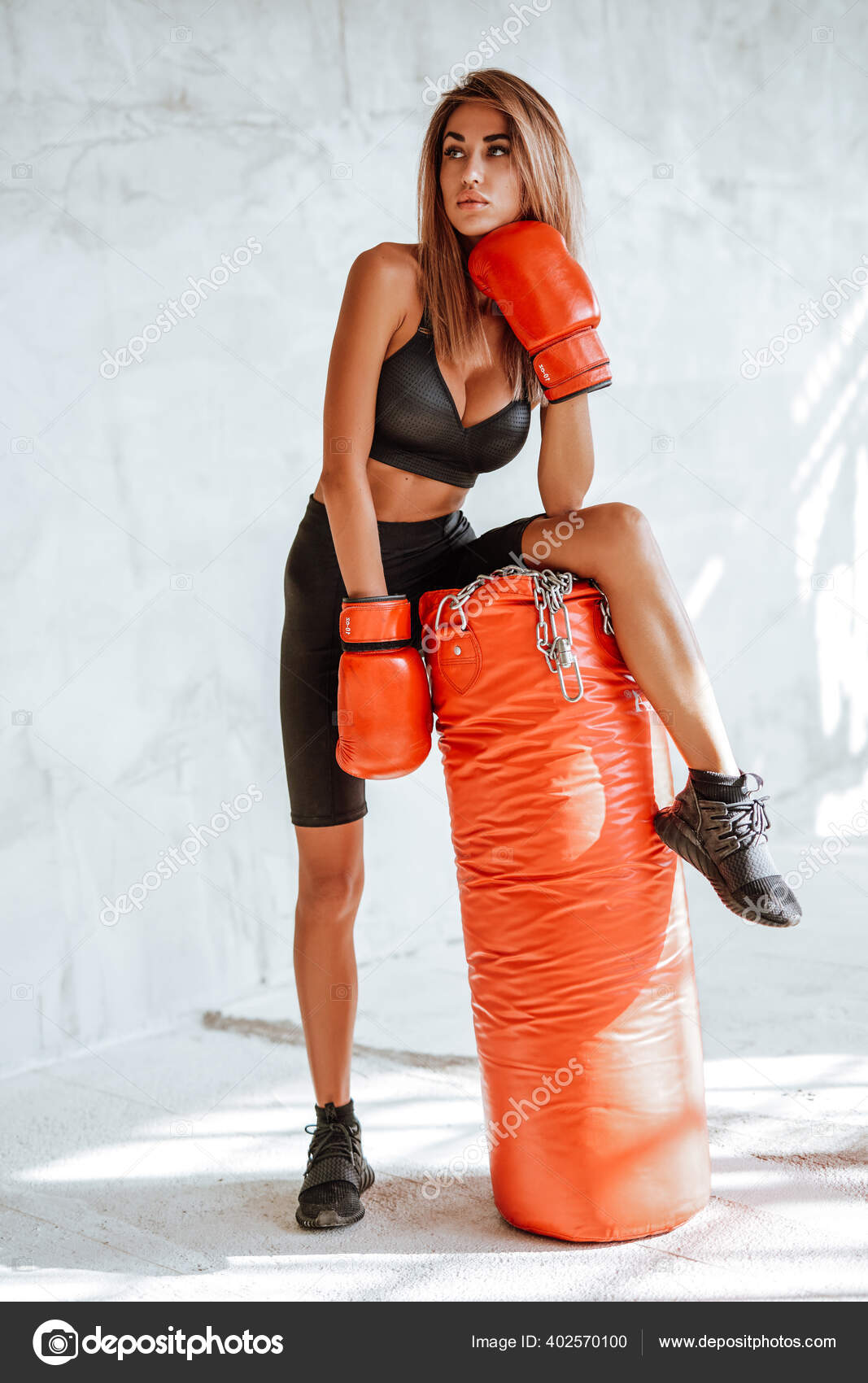 Chica muy bonita en un chándal negro con un saco de boxeo y guantes de boxeo:  fotografía de stock © fxquadro #402570100