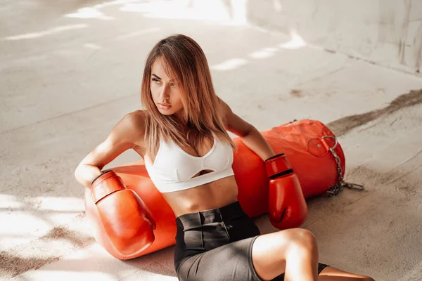 Jolie sportive assise sur le sol avec un sac de boxe. — Photo