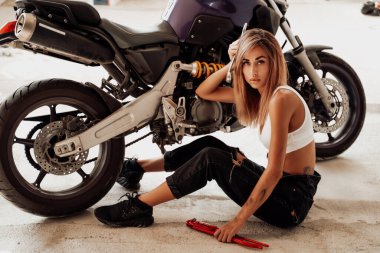 İngiliz anahtarlı şehvetli kız spor bir motosikletle poz veriyor.