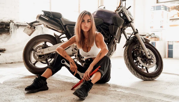 Het tjej med skiftnycklar poserar med en sport lila motorcykel — Stockfoto