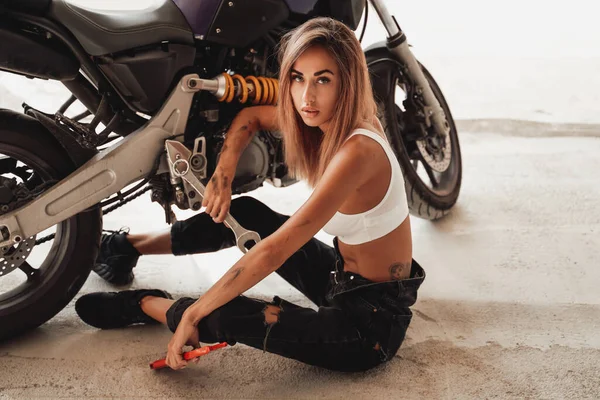 Горячая девушка с ключами позирует со спортивным мотоциклом — стоковое фото