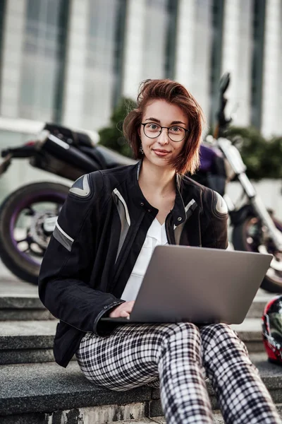 Jovem senhora de negócios senta-se perto de sua moto roxa com seu novo computador — Fotografia de Stock