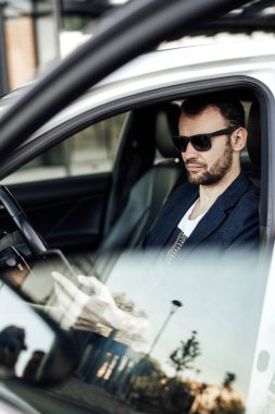 Moda zengini adam telefona bakıyor ve arabada oturuyor.