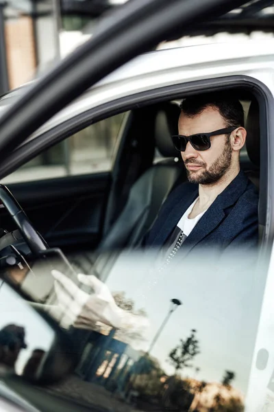 Fashion rich man looking at phone and sitting in the car — Stock Photo, Image