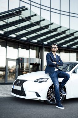 Ciddi bir erkek girişimci arabasıyla şehirde duruyor.