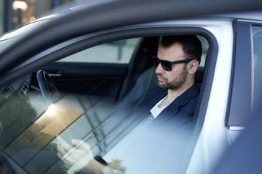 Bir girişimci arabasının içinde bazı anlaşmalar yapmak için araba kullanıyor.