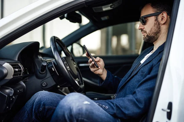 Mode rijke man op zoek naar telefoon en zitten in de auto — Stockfoto