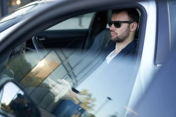Un hombre de negocios adulto está sentado en su coche nuevo y mirando algunas noticias — Foto de Stock