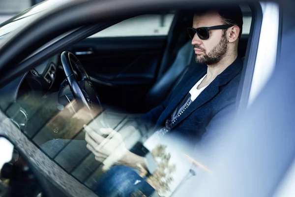 Moda zengini adam telefona bakıyor ve arabada oturuyor. — Stok fotoğraf