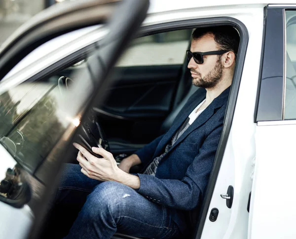 Модный богач смотрит в телефон и сидит в машине — стоковое фото