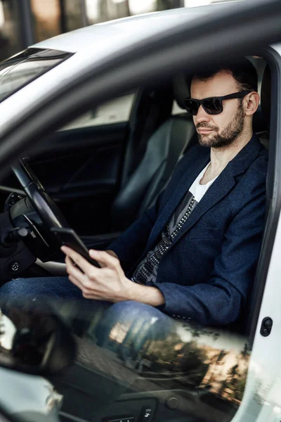 Moda homem rico olhando para o telefone e sentado no carro — Fotografia de Stock