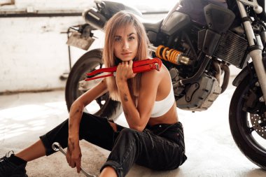 Elinde bazı aletler olan güzel sarışın bir kızla modern bir motosiklet.