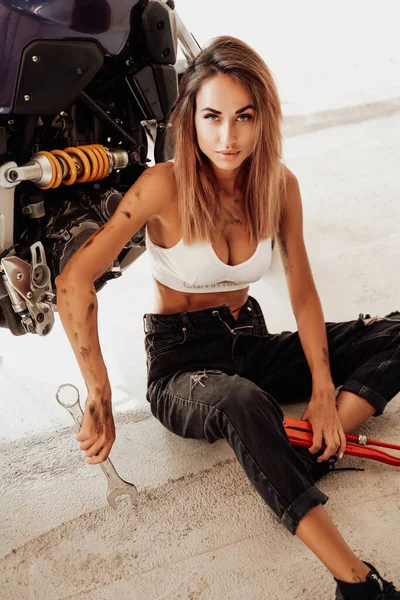 Female cute technician and modern sport motorbike in bright garage — Stock Photo, Image