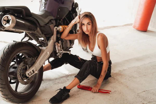 Garage indoors and cute girl with custom motorbike — Stock Photo, Image